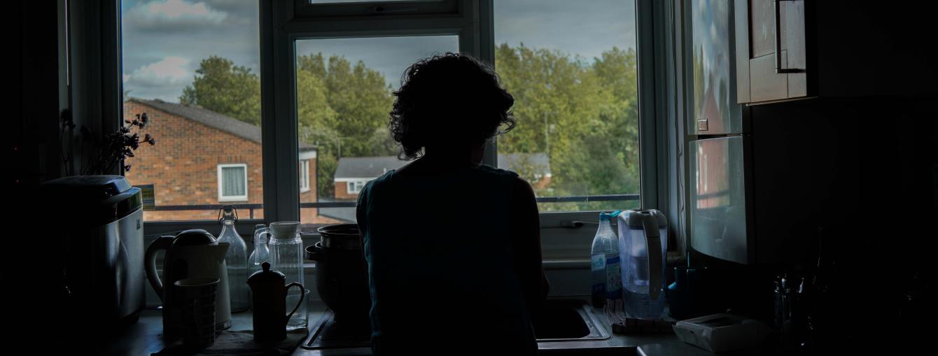 Silhoutte of a female client standing at kitchen sink by window