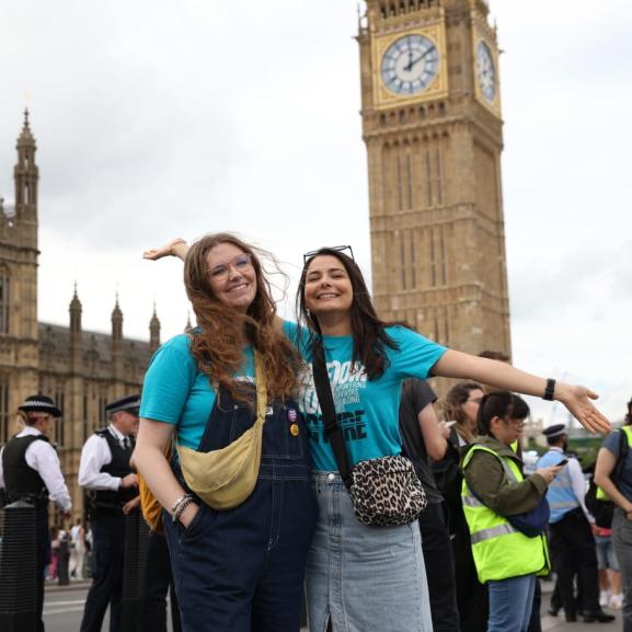 Two young women smiling at the camera outside Parliament