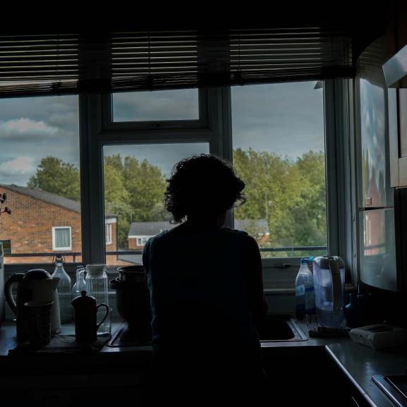 Silhoutte of a female client standing at kitchen sink by window