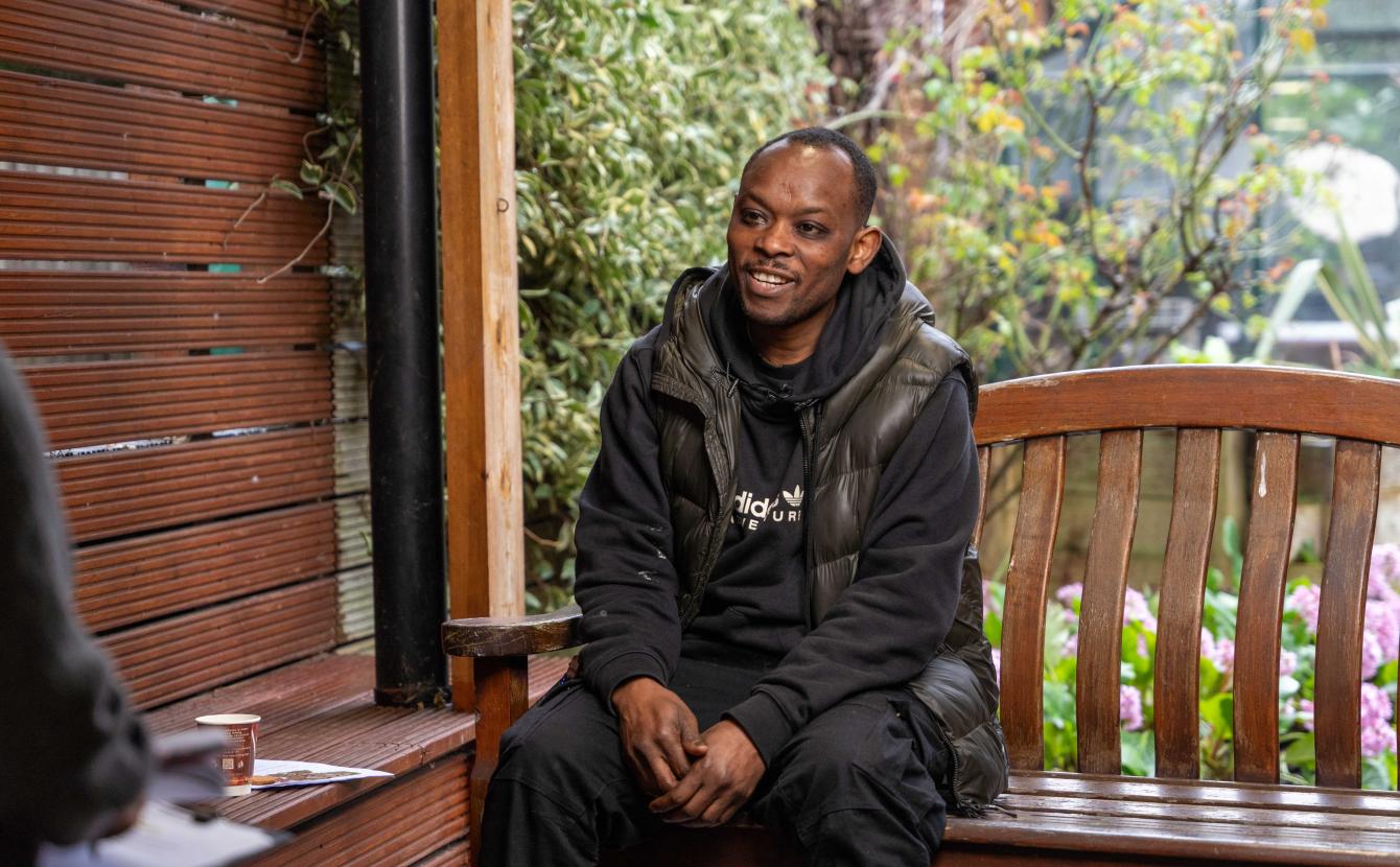 Middle aged man sitting on an outdoor bench smiling