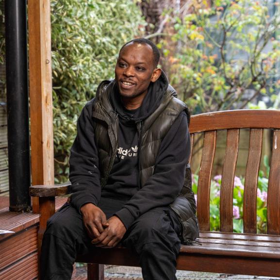 Middle aged man sitting on an outdoor bench smiling