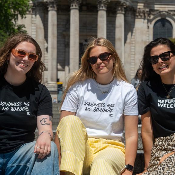 Three women posing with t-shirts