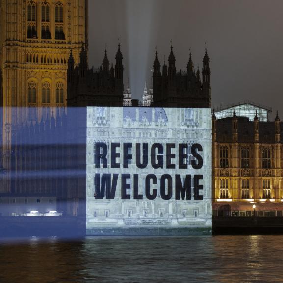 Projection on parliament reading "Refugees welcome"