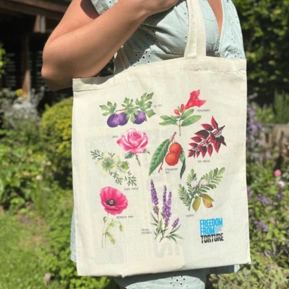 A woman holding a tote bag with plant illustrations on it