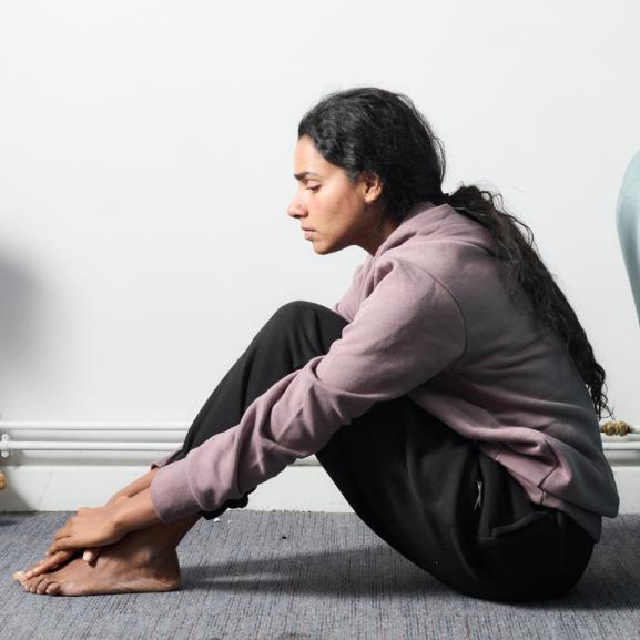 Young South Asian woman sitting on the floor looking sad