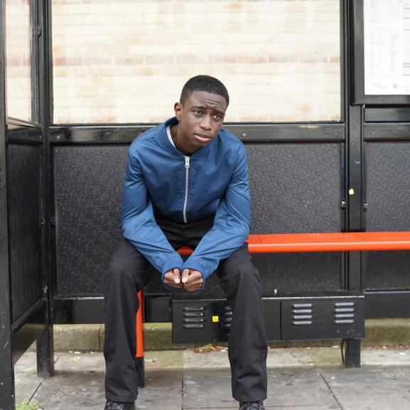 Teenager sitting at a bus stop