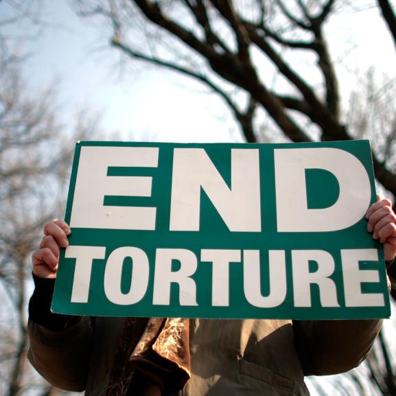 A person holds a sign that reads 'End torture'