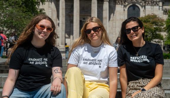 Three women posing with t-shirts
